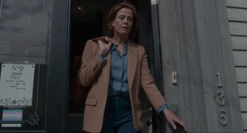 Movie still from “The Good House” (2021), directed by Maya Forbes – A woman wearing a brown jacket and blue pants; Medium shot, Low angle