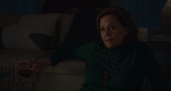 Movie still from “The Good House” (2021), directed by Maya Forbes – A woman sitting on a couch in a dark room; Medium shot, Over the shoulder angle