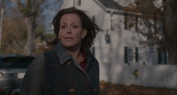 Movie still from “The Good House” (2021), directed by Maya Forbes – A woman in a plaid jacket standing in front of a white house; Medium shot, Over the shoulder angle