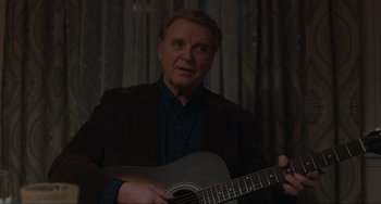 Movie still from “The Good House” (2021), directed by Maya Forbes – A man holding a guitar in front of a curtain; Close Up shot, Over the shoulder angle
