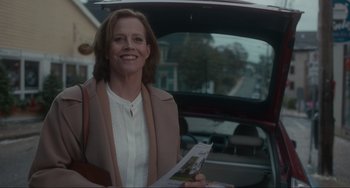 Movie still from “The Good House” (2021), directed by Maya Forbes – A woman standing in front of a car holding a newspaper; Medium shot, Over the shoulder angle