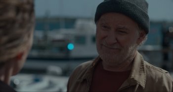 Movie still from “The Good House” (2021), directed by Maya Forbes – An older man wearing a hat standing in front of boats; Close Up shot, Over the shoulder angle