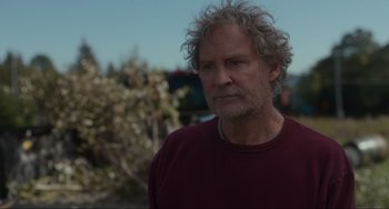 Movie still from “The Good House” (2021), directed by Maya Forbes – An older man with gray curly hair wearing a maroon shirt; Close Up shot, Over the shoulder angle