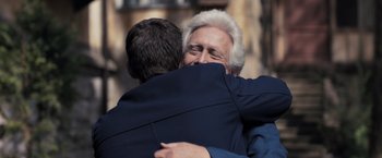 Movie still from “The Good Neighbor” (2022), directed by Stephan Rick – Two men hugging each other in front of a building; Close Up shot, Over the shoulder angle