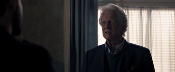 Movie still from “The Good Neighbor” (2022), directed by Stephan Rick – An older man with white hair looking at the camera; Close Up shot, Over the shoulder angle