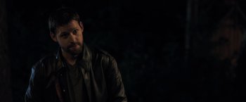 Movie still from “The Good Neighbor” (2022), directed by Stephan Rick – A man wearing a leather jacket standing in the dark; Close Up shot, Over the shoulder angle