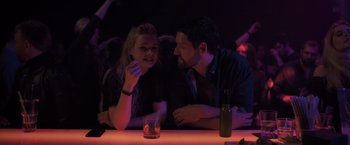 Movie still from “The Good Neighbor” (2022), directed by Stephan Rick – A man and a woman sitting at a bar; Medium shot, Over the shoulder angle