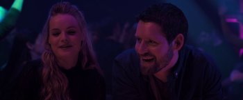 Movie still from “The Good Neighbor” (2022), directed by Stephan Rick – A man and a woman smile brightly at a party; Close Up shot, Over the shoulder angle