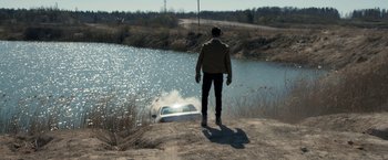 Movie still from “The Good Neighbor” (2022), directed by Stephan Rick – A man standing next to a car in a body of water; Wide shot, High angle