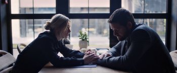 Movie still from “The Good Neighbor” (2022), directed by Stephan Rick – A man and a woman holding hands on a table; Medium shot, Over the shoulder angle