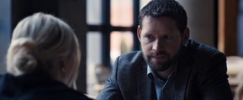 Movie still from “The Good Neighbor” (2022), directed by Stephan Rick – A man and a woman sitting at a table in front of a window; Close Up shot, Over the shoulder angle