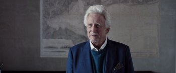 Movie still from “The Good Neighbor” (2022), directed by Stephan Rick – An older man in a blue suit and white shirt; Close Up shot, Low angle