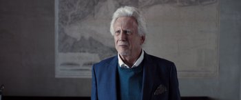 Movie still from “The Good Neighbor” (2022), directed by Stephan Rick – An older man in a blue suit and white shirt; Close Up shot, Low angle