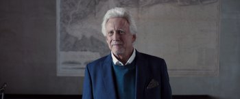 Movie still from “The Good Neighbor” (2022), directed by Stephan Rick – An older man with white hair and a blue jacket; Close Up shot, Low angle