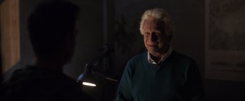 Movie still from “The Good Neighbor” (2022), directed by Stephan Rick – An older man in a blue sweater is smiling; Close Up shot, Over the shoulder angle