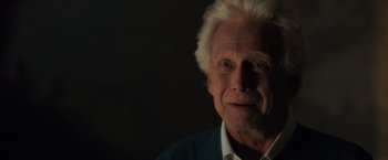 Movie still from “The Good Neighbor” (2022), directed by Stephan Rick – An older man with white hair is smiling for the camera; Close Up shot, Over the shoulder angle