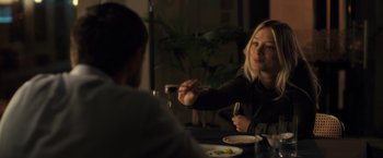 Movie still from “The Good Neighbor” (2022), directed by Stephan Rick – Two people sitting at a table with a plate of food; Medium shot, Over the shoulder angle