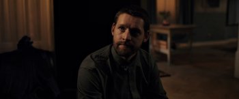 Movie still from “The Good Neighbor” (2022), directed by Stephan Rick – A man sitting in a dark room with his eyes closed; Close Up shot, Over the shoulder angle