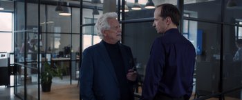 Movie still from “The Good Neighbor” (2022), directed by Stephan Rick – Two men are talking in an office setting; Medium shot, Over the shoulder angle