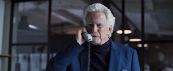 Movie still from “The Good Neighbor” (2022), directed by Stephan Rick – An older man talking on a phone while wearing a suit; Close Up shot, Low angle