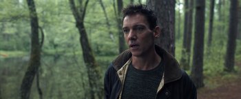 Movie still from “The Good Neighbor” (2022), directed by Stephan Rick – A person standing in the woods; Close Up shot, Over the shoulder angle