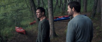 Movie still from “The Good Neighbor” (2022), directed by Stephan Rick – Two men standing next to each other in the woods; Wide shot, High angle