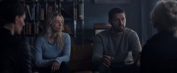 Movie still from “The Good Neighbor” (2022), directed by Stephan Rick – A man and a woman sitting next to each other on a couch; Medium shot, Over the shoulder angle