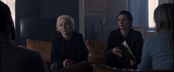 Movie still from “The Good Neighbor” (2022), directed by Stephan Rick – Two women sitting on a couch in front of a window; Medium shot, Over the shoulder angle