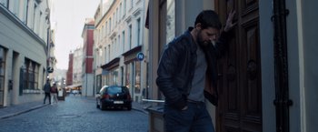 Movie still from “The Good Neighbor” (2022), directed by Stephan Rick – A man leaning against a wall on a street corner; Medium shot, Low angle