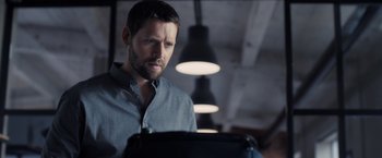 Movie still from “The Good Neighbor” (2022), directed by Stephan Rick – A man in a blue dress shirt is looking at the camera; Close Up shot, Low angle