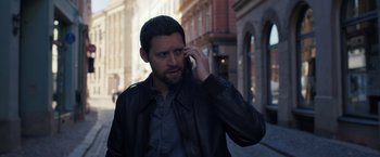 Movie still from “The Good Neighbor” (2022), directed by Stephan Rick – A man talking on a cell phone while standing on the street; Close Up shot, High angle