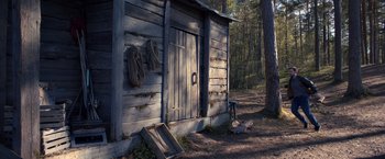 Movie still from “The Good Neighbor” (2022), directed by Stephan Rick – An old wooden building in the middle of a forest; Extreme Wide shot, Low angle