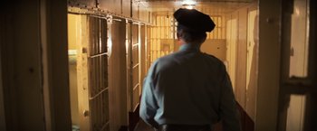 Movie still from “The Goonies” (1985), directed by Richard Donner – A man wearing a police hat in a jail cell; Wide shot, High angle