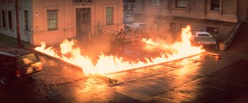 Movie still from “The Goonies” (1985), directed by Richard Donner – A man standing in front of a fire on the street; Extreme Wide shot, High angle