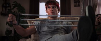 Movie still from “The Goonies” (1985), directed by Richard Donner – A man sitting in a chair with a red bandanna on his head; Medium shot, Low angle
