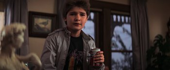 Movie still from “The Goonies” (1985), directed by Richard Donner – A young man holding a can of soda in his hand; Medium shot, Over the shoulder angle