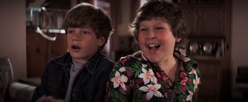 Movie still from “The Goonies” (1985), directed by Richard Donner – Two young boys are smiling for the camera; Close Up shot, High angle