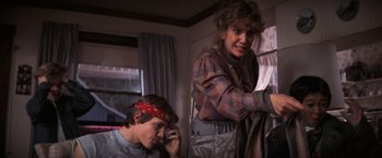 Movie still from “The Goonies” (1985), directed by Richard Donner – A woman and a boy are sitting in a living room; Medium shot, Low angle