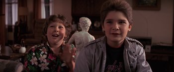 Movie still from “The Goonies” (1985), directed by Richard Donner – Two young children standing in front of a statue; Medium shot, Low angle