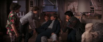 Movie still from “The Goonies” (1985), directed by Richard Donner – A group of young men sitting in a living room together; Medium shot, High angle