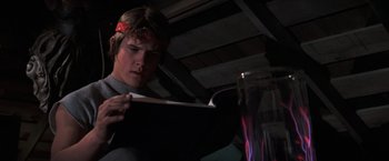 Movie still from “The Goonies” (1985), directed by Richard Donner – A young man is reading a book in a dark room; Close Up shot, Low angle