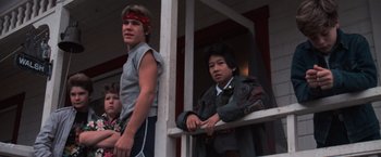 Movie still from “The Goonies” (1985), directed by Richard Donner – Two young men sitting next to each other on a balcony; Medium shot, Low angle