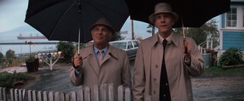 Movie still from “The Goonies” (1985), directed by Richard Donner – A man holding an umbrella while standing next to another man; Medium shot, Low angle