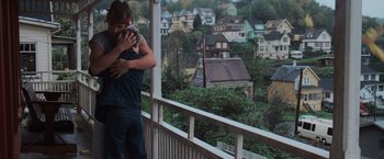 Movie still from “The Goonies” (1985), directed by Richard Donner – A man standing on a balcony holding a cat; Medium shot, High angle