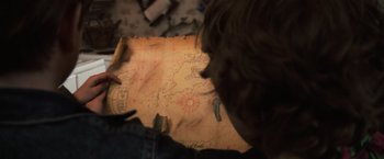 Movie still from “The Goonies” (1985), directed by Richard Donner – A person looking at a map of the world; Extreme Close Up shot, Overhead angle