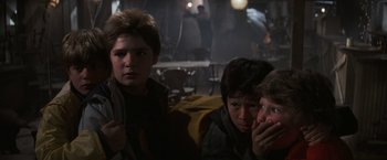 Movie still from “The Goonies” (1985), directed by Richard Donner – A group of young boys sitting next to each other; Medium shot, Over the shoulder angle