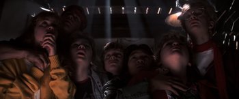 Movie still from “The Goonies” (1985), directed by Richard Donner – A group of people that are looking up at the sky; Medium shot, Low angle