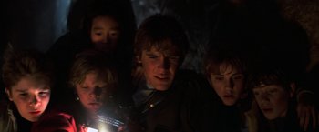 Movie still from “The Goonies” (1985), directed by Richard Donner – A group of young people standing in the dark; Close Up shot, Low angle