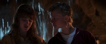 Movie still from “The Goonies” (1985), directed by Richard Donner – A young man and a young woman standing next to each other in front of a waterfall; Close Up shot, Low angle
