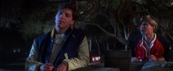 Movie still from “The Goonies” (1985), directed by Richard Donner – A man sitting at a table in front of a tree; Close Up shot, Over the shoulder angle